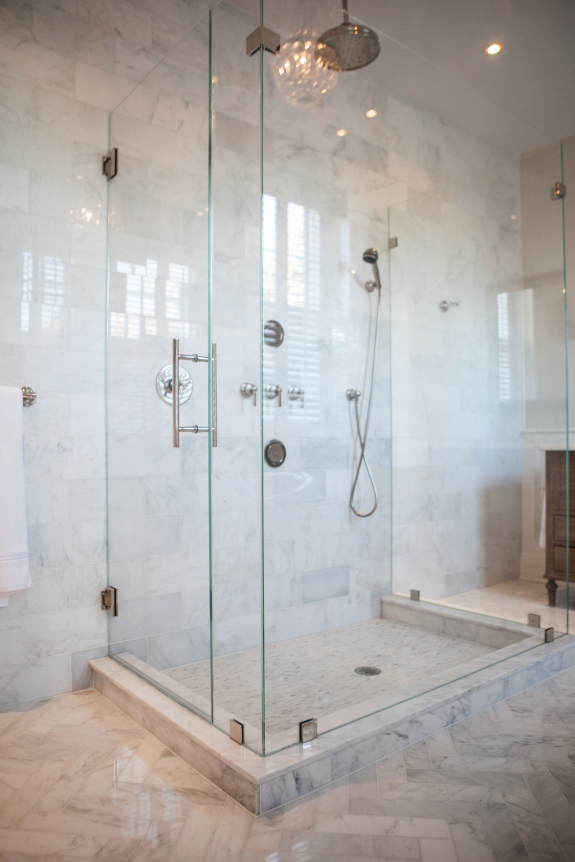 Crystal clear shower reflects crystal chandelier in luminous Master Bath.